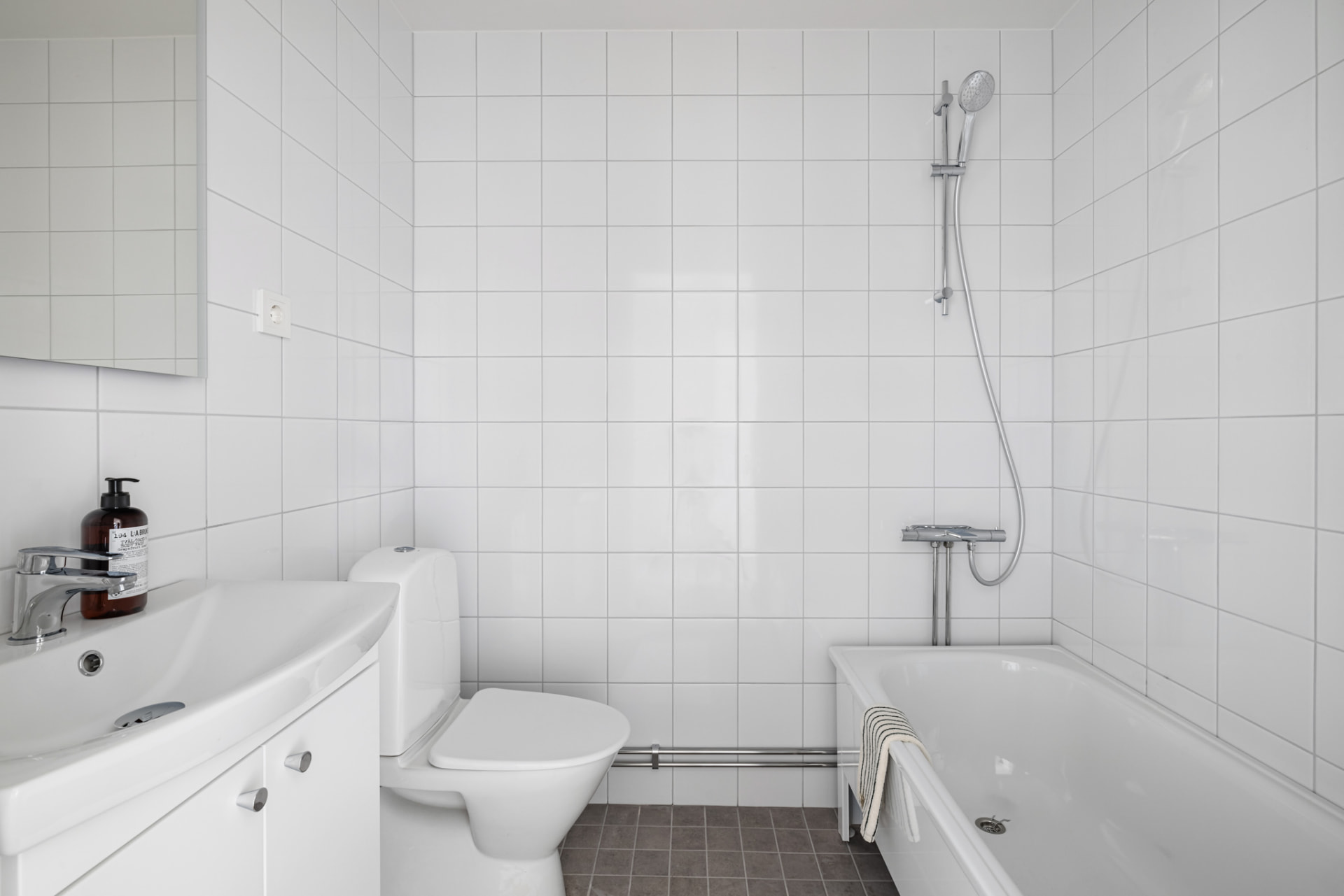 Badrum med badkar, kommod med tvättställ och WC.