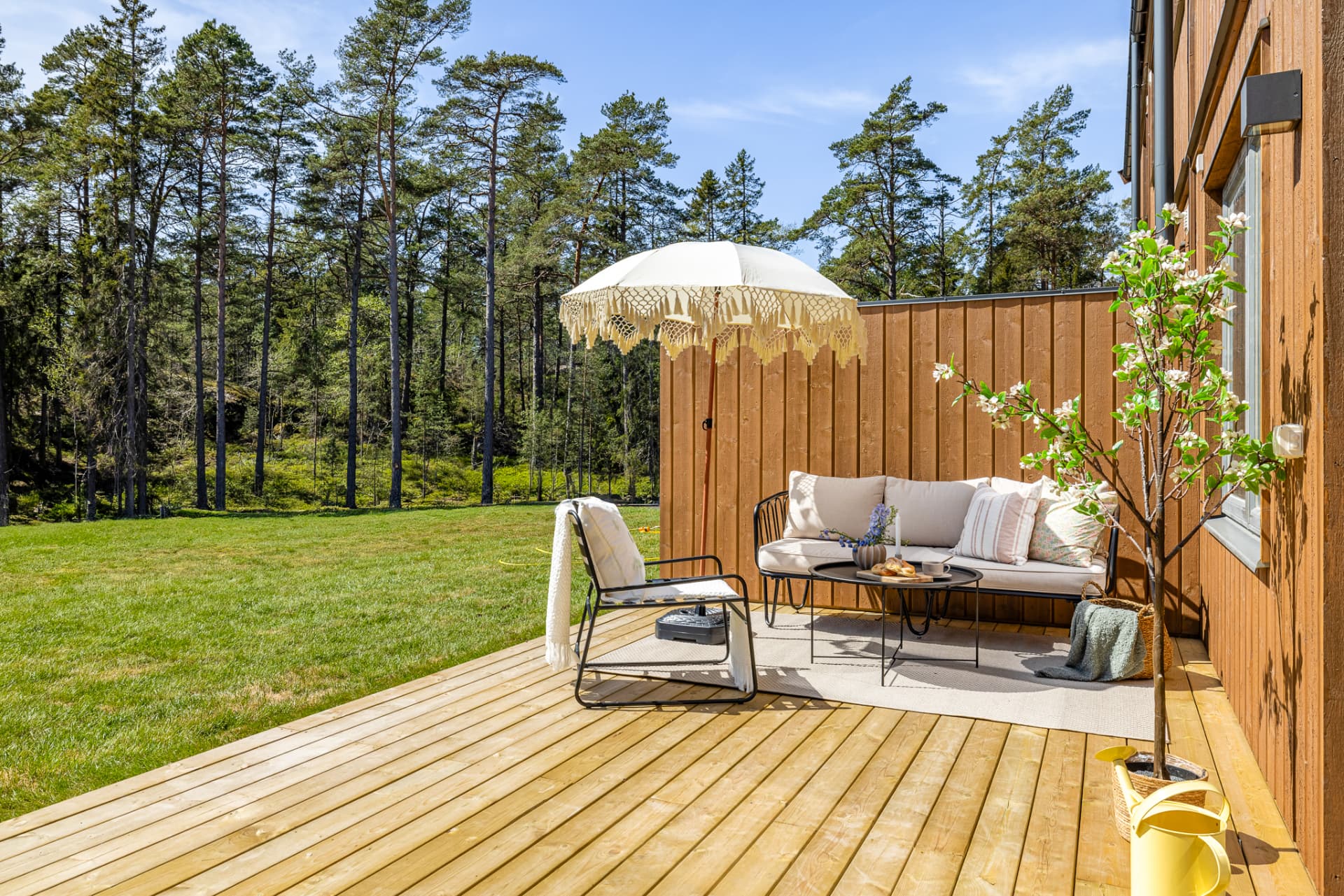 Egen uteplats med trätrall som förlänger hemmet ut i det gröna. Generösa ytor ger plats för både matgrupp, grill och avkoppling.