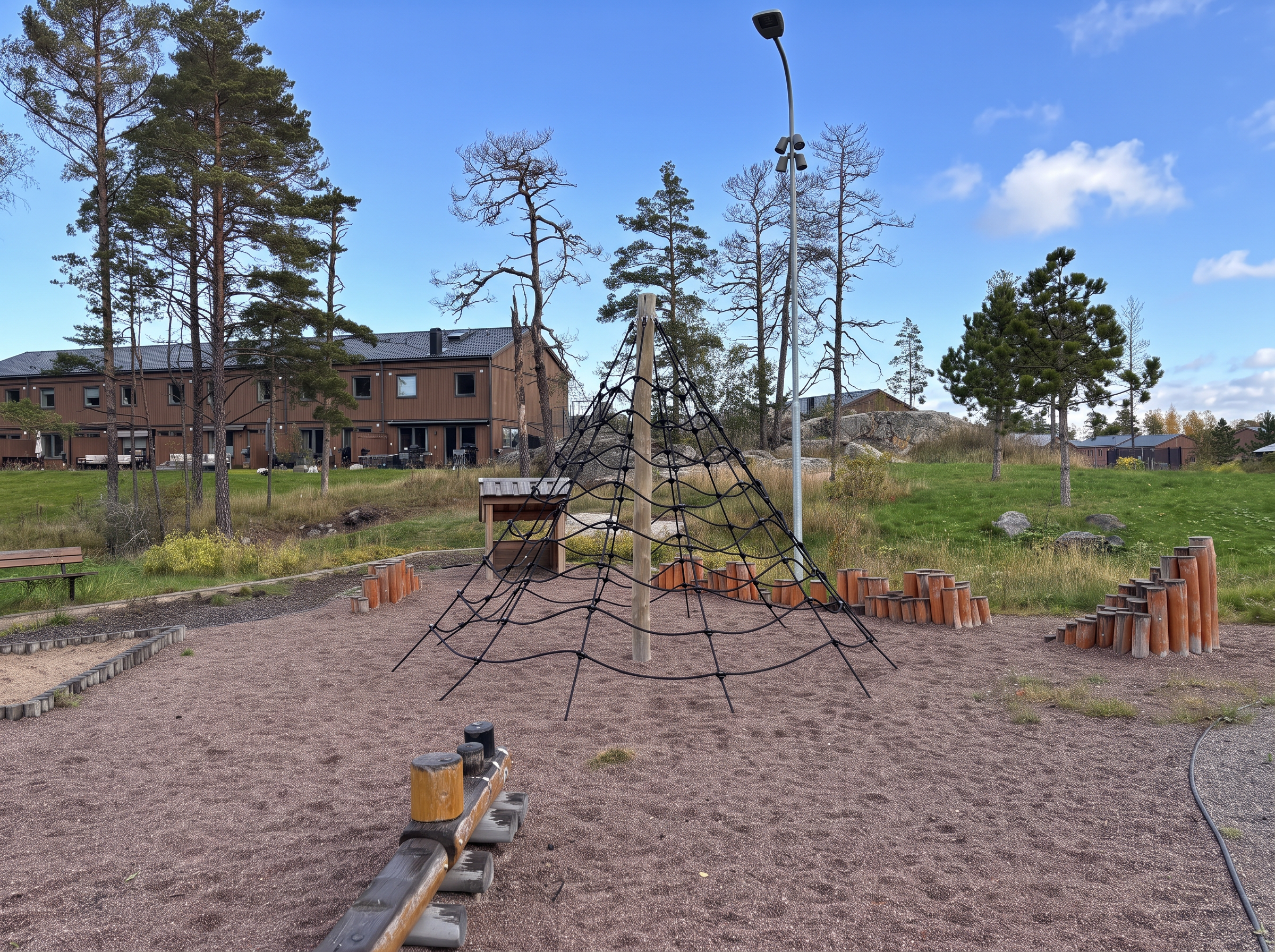 En av områdets två lekplatser – med klätternät, balansstockar och sandlåda mitt bland tallarna, bara några steg från hemmet.